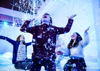 Three young people play in the falling snow. They look excited and happy.